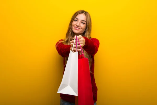 Menina Fundo Amarelo Vibrante Segurando Monte Sacos Compras — Fotografia de Stock