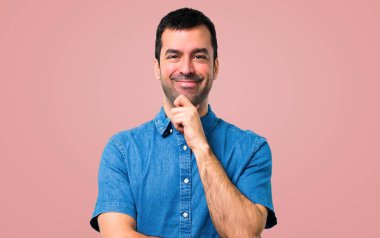Yakışıklı adam ayakta ve pembe bir arka plan üzerinde bir fikir düşünce mavi gömlek ile