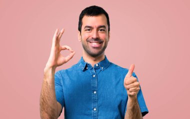 Bir ok işareti ile parmak pembe arka plan üzerinde gösterilen mavi gömlek ile yakışıklı adam