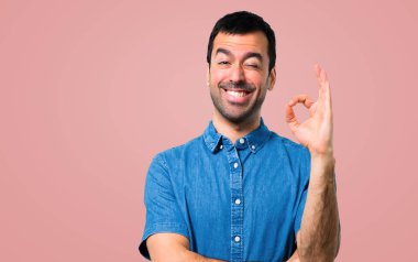 Bir ok işareti ile parmak pembe arka plan üzerinde gösterilen mavi gömlek ile yakışıklı adam