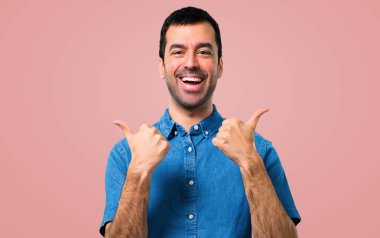 Jest Yaşasın vererek ve pembe arka plan gülümseyen mavi gömlek ile yakışıklı adam