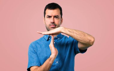 Mavi gömlek yapma dur jestle elinde pembe bir arka plan ile yakışıklı adam
