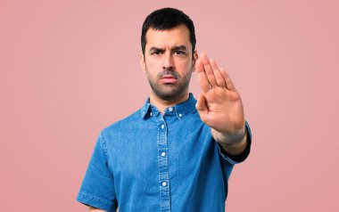 Mavi gömlek yapma dur jestle elinde pembe bir arka plan ile yakışıklı adam