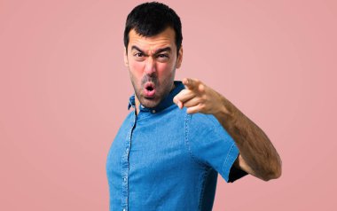 Kızgın ve Öfkeli öfkeli harekete pembe bir arka plan üzerinde mavi gömlek ile yakışıklı adam
