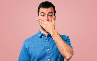 Ağız pembe bir arka plan üzerinde elleriyle kapsayan mavi gömlek ile yakışıklı adam