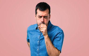 Mavi gömlek ile yakışıklı adam öksürük ile acı ve pembe arka plan kötü hissediyor