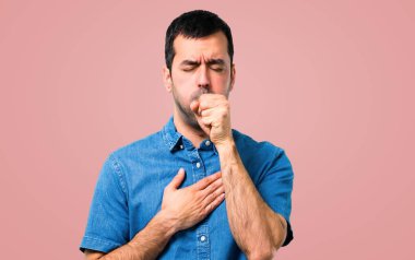 Mavi gömlek ile yakışıklı adam öksürük ile acı ve pembe arka plan kötü hissediyor