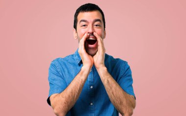Mavi gömlek, pembe arka plan açık ağız ile bağırarak ile yakışıklı adam