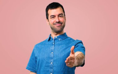 Pembe bir arka plan üzerinde iyi bir anlaşma sonra mavi gömlek el sıkışma ile yakışıklı adam