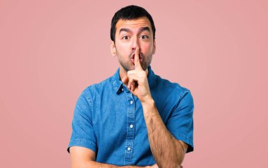 Ağız ve sessizlik bir jest pembe bir arka plan üzerinde kapanış bir işaret gösteren mavi gömlek ile yakışıklı adam