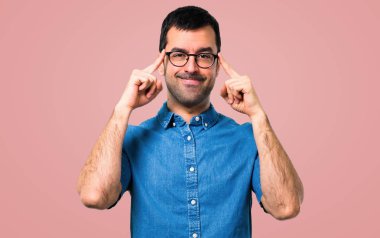 Yakışıklı adam mavi gömlek ve pembe bir arka plan üzerinde gözlük