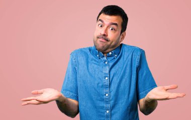 Mavi gömlek, pembe arka plan önemsiz jest yapma ile yakışıklı adam