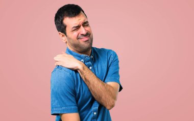 Omuz ağrısı pembe bir arka plan üzerinde mavi gömlek ile yakışıklı adam