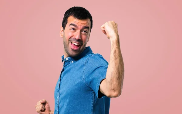 英俊的人与蓝色衬衫庆祝胜利在粉红色的背景 — 图库照片