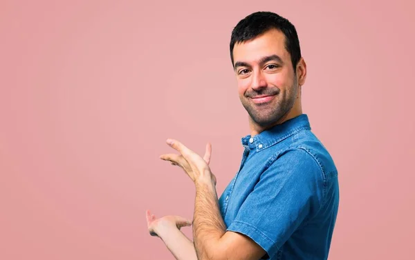 Knappe Man Met Blauwe Shirt Presenteren Uitnodigen Komen Roze Achtergrond — Stockfoto