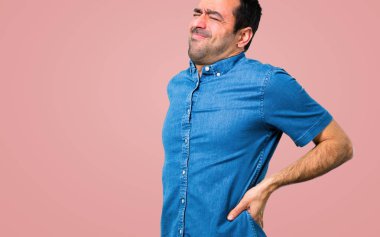 Pembe bir arka plan üzerinde sırt ağrısı ile mavi gömlek ile yakışıklı adam