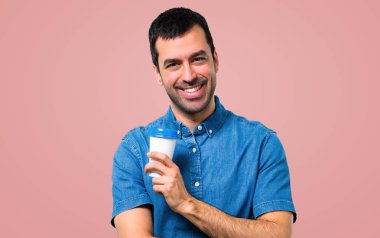 Pembe arka plan götürmeye yakışıklı adamla kahve tutan mavi gömlek
