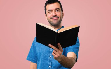 Mavi gömlek pembe bir arka plan üzerine bir kitap okuma ile yakışıklı adam