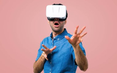 Vr gözlükle pembe arka plan mavi gömlek ile yakışıklı adam