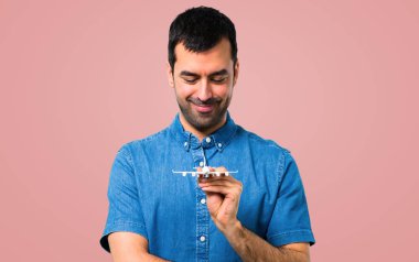 Mavi gömlek pembe bir oyuncak uçak holding ile yakışıklı adam