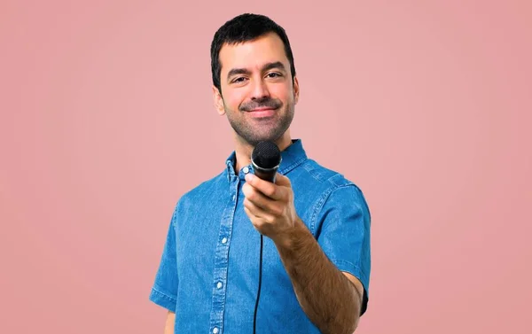 青いシャツ ピンク背景のマイクを使って歌うとハンサムな男 — ストック写真