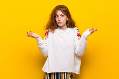 Sarı duvar eller ve omuzlar yetiştirme süre şüpheleri genç Kızıl saçlı kadın