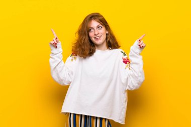 Harika bir fikir işaret parmağı ile işaret sarı duvar genç Kızıl saçlı kadın
