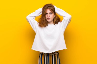 Genç Kızıl saçlı kadın sarı duvarın üzerinden alır Eller başının üstüne çünkü migren vardır