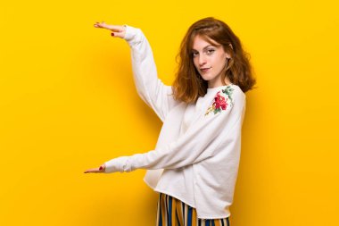 Bir reklam eklemek için sarı duvar boşaltmak tutan genç Kızıl saçlı kadın