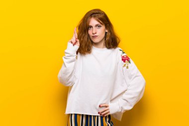 En iyi dilek ve geçiş parmaklarıyla sarı duvar genç Kızıl saçlı kadın