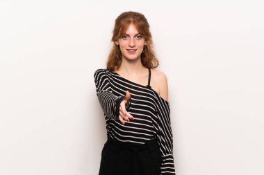 Beyaz duvar iyi bir anlaşma kapanış için el sıkışan genç Kızıl saçlı kadın