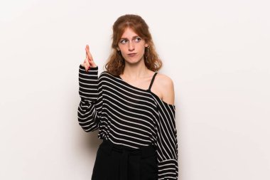 En iyi dilek ve geçiş parmak ile beyaz duvar genç Kızıl saçlı kadın