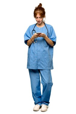 Tam uzunlukta bir atış bir genç redhead hemşire izole beyaz arka plan üzerinde mobil ileti gönderme