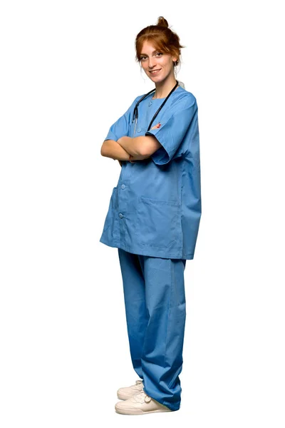 一个年轻的红头发的护士的全长镜头 双臂交叉 并期待着在孤立的白色背景 — 图库照片