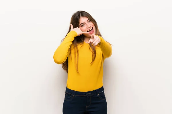 電話のジェスチャーを作ると正面を指している黄色のセーターを持つ若い女性 — ストック写真