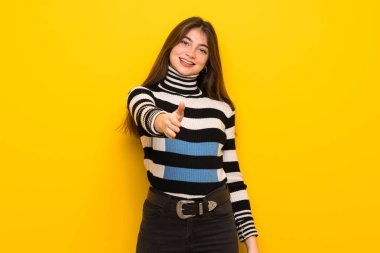 İyi bir anlaşma kapanış için el sıkışan sarı duvarın üzerinden genç kadın