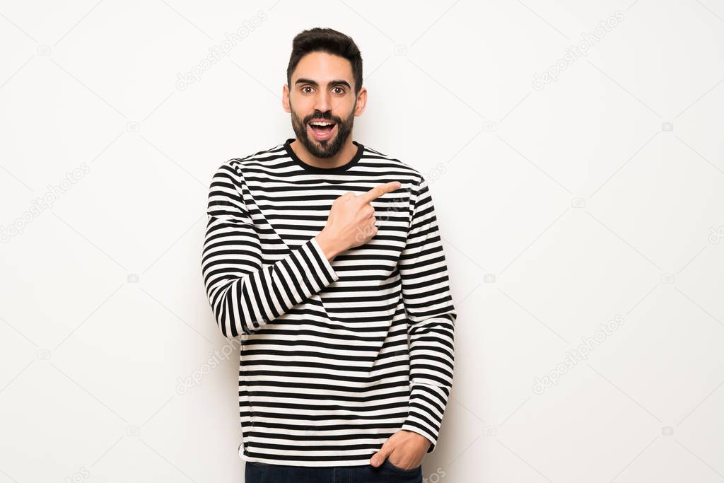 handsome man with striped shirt pointing to the side to present a product