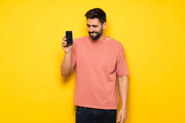 Bonito Homem Sobre Parede Amarela Com Conturbado Segurando Smartphone Quebrado — Fotografia de Stock