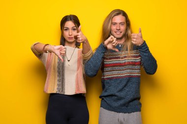 Hippi çift iyi-kötü işaret yapma sarı arka plan üzerinde. Arasında kararsız Evet ya da değil