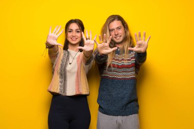 Hippi çift on parmak ile sayma sarı arka plan üzerinde