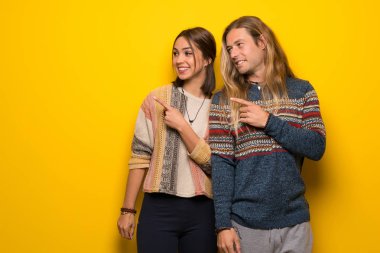 Hippi çift ürün sunmak için tarafına işaret sarı arka plan üzerinde