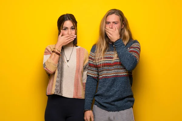 Hippie Casal Sobre Fundo Amarelo Cobrindo Boca Com Mãos Para — Fotografia de Stock