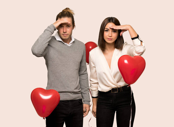 Couple in valentine day looking far away with hand to look something over isolated background