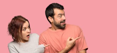 İki Sevgililer günü işaret parmağı izole pembe bir arka plan üzerinde sürpriz bir yüz yanında içinde