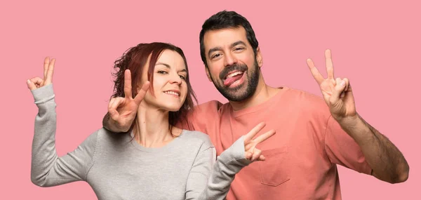 Pareja San Valentín Sonriendo Mostrando Signo Victoria Sobre Fondo Rosa —  Fotos de Stock