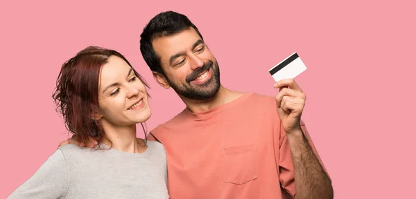 Couple Valentine Day Holding Credit Card Thinking Isolated Pink Background — Stock Photo, Image