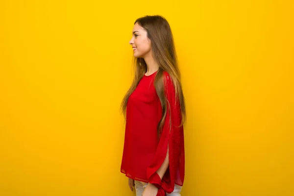 Menina Com Vestido Vermelho Sobre Parede Amarela Posição Lateral — Fotografia de Stock