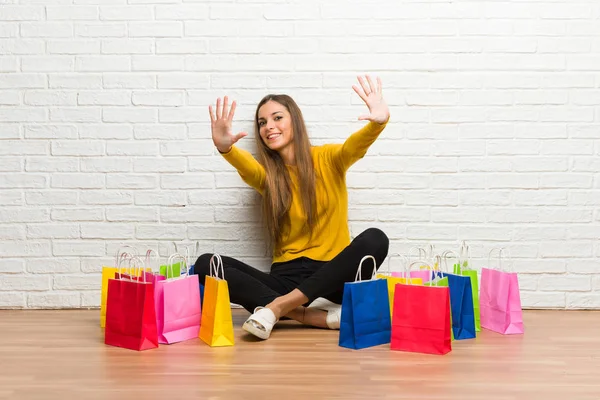 Young girl with lot of shopping bags counting ten with fingers