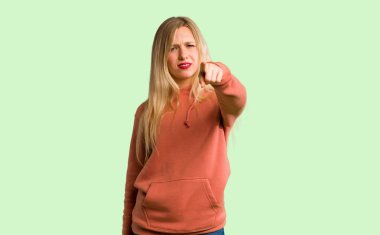 Genç kız kötü bir durum ve açık yeşil arka plan üzerinde göstererek sinirli
