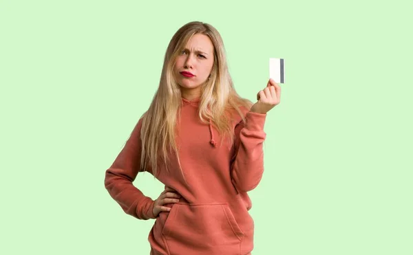 年轻女孩拿信用卡没有金钱在绿色背景 — 图库照片